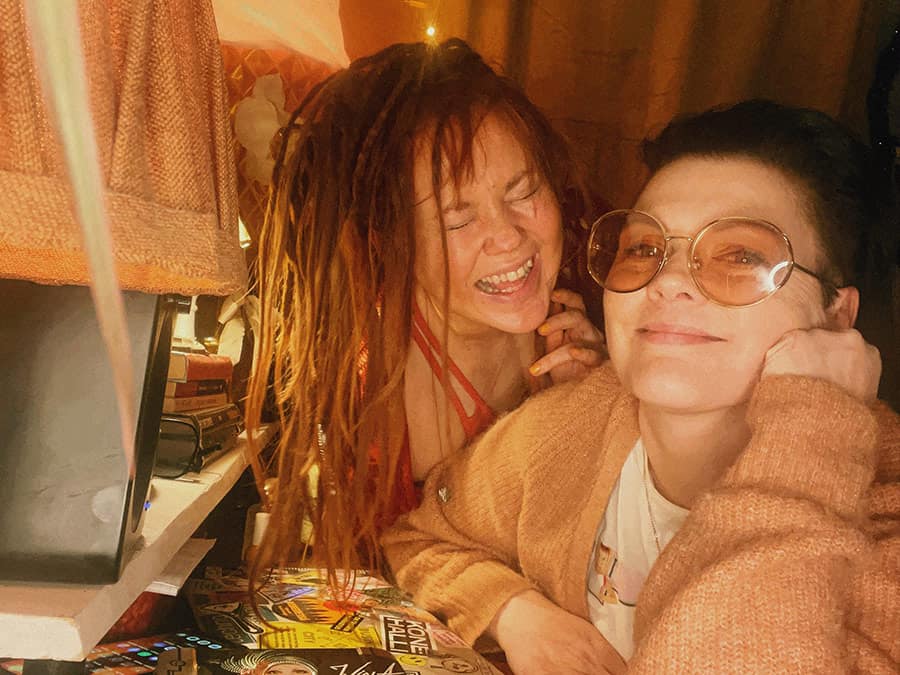 Wiola and Korso laughing together, one with dreadlocks and one in round glasses