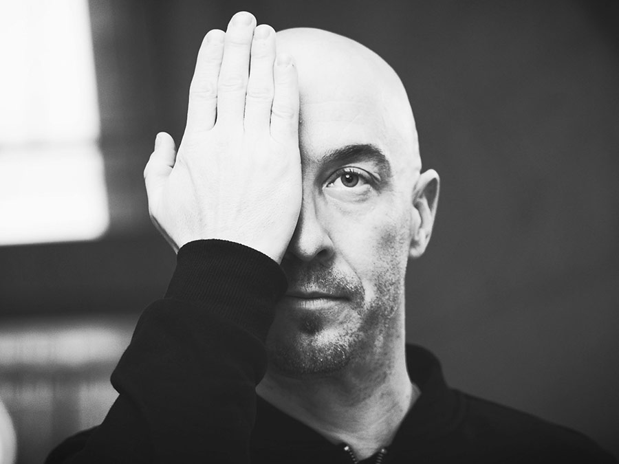 Black-and-white portrait of Niko Geselle covering one eye with his hand