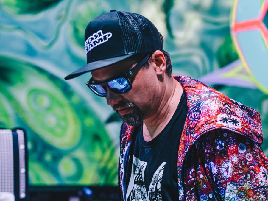 Igor Swamp in a cap and patterned jacket, looking down at his equipment