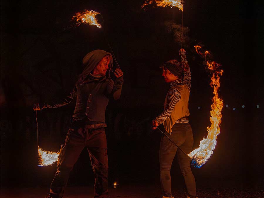 Two Synkronia performers spinning fire props in the dark