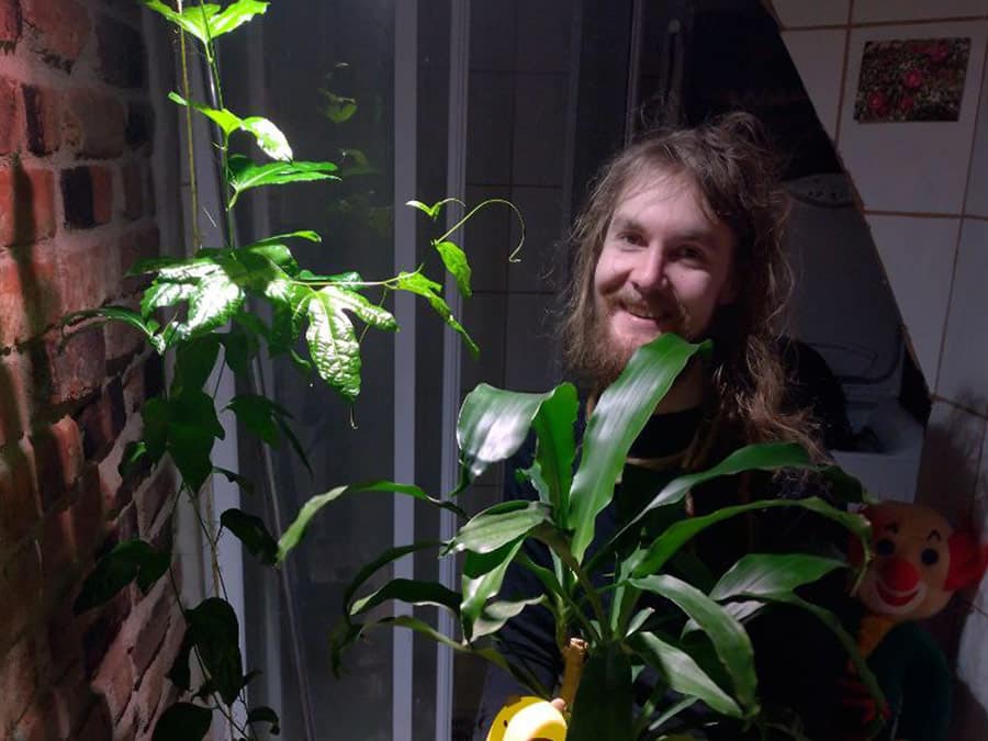 Akubara with long hair smiling among houseplants