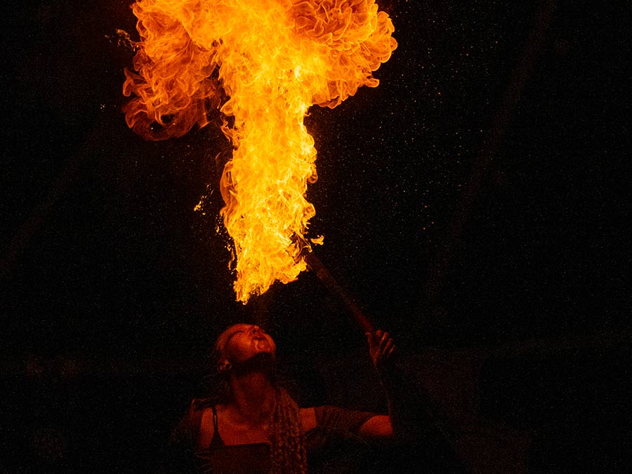 A fire performer breathing a huge fireball into the night