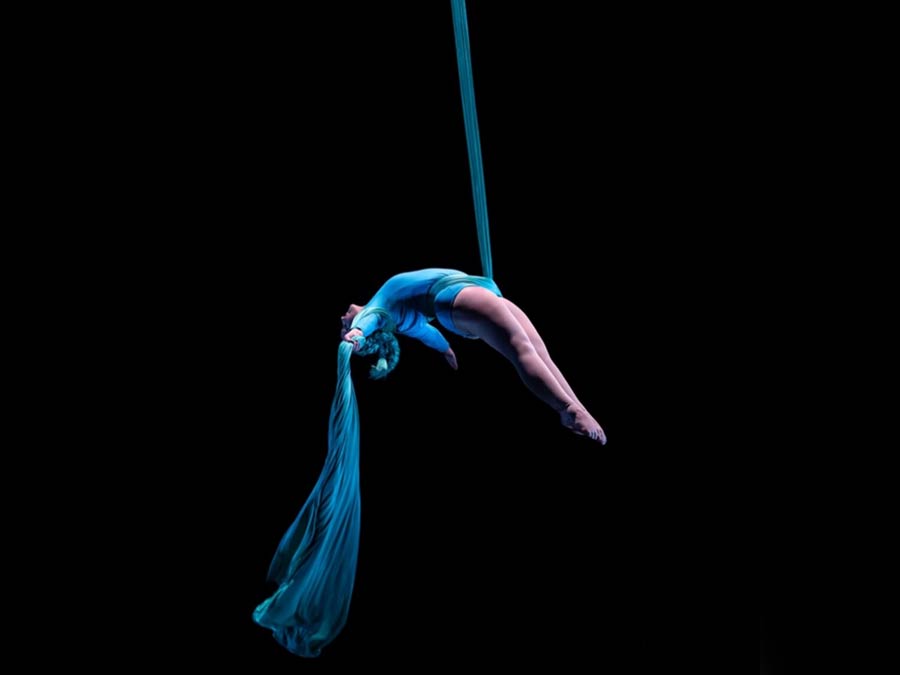 Karita performing on blue aerial silks against a black background