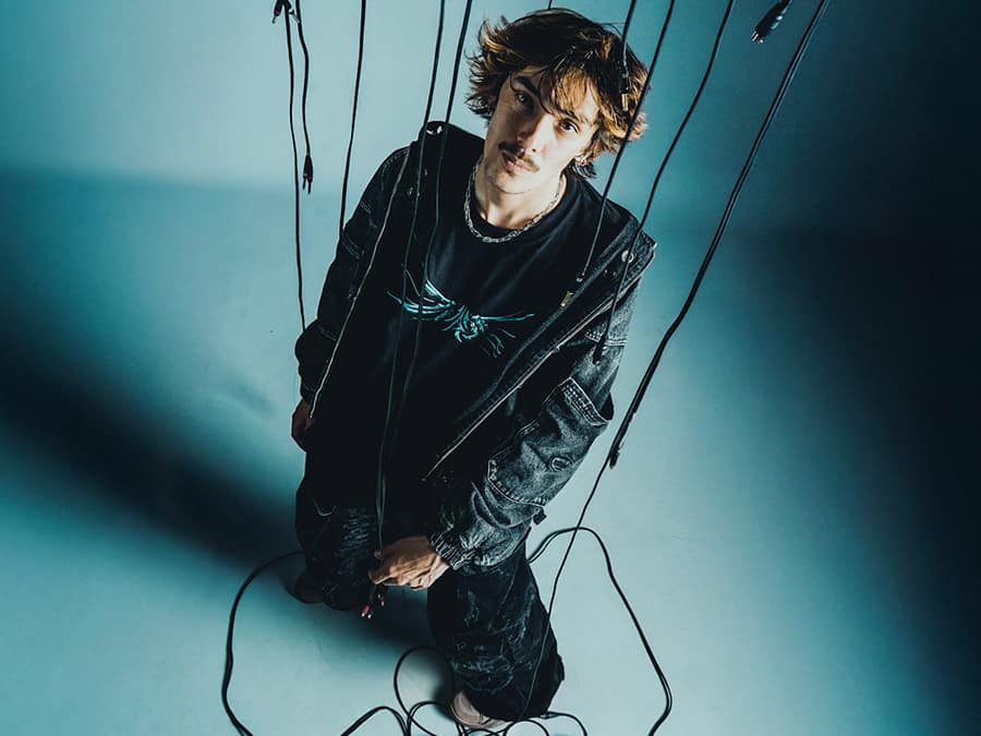 DICA crouching on the floor among hanging cables, photographed from above