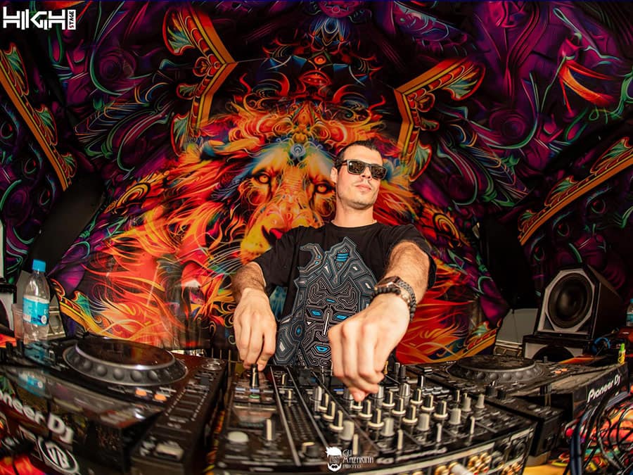 UkaUka in sunglasses playing at the decks under a psychedelic backdrop