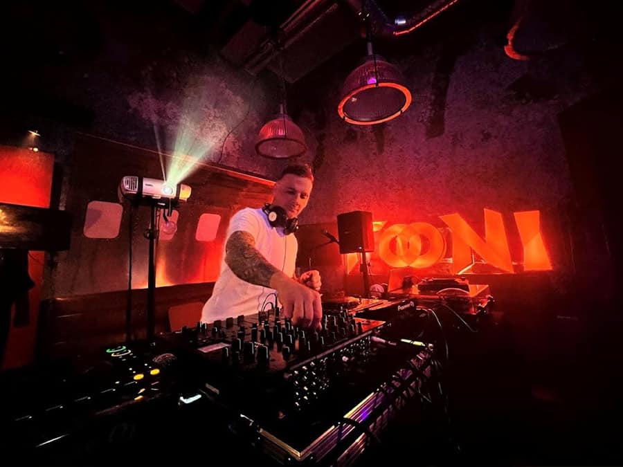 TsoniBoy at the decks on a club stage lit in red