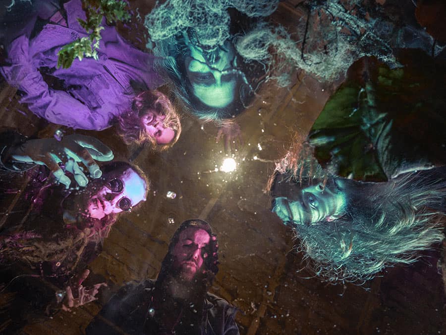 The members of Tomumaja lying on the ground, photographed from above in eerie green light
