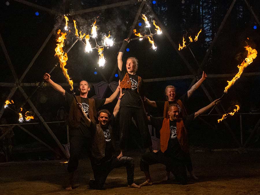 The TuliZukka group posing with flaming fans and torches under a dome
