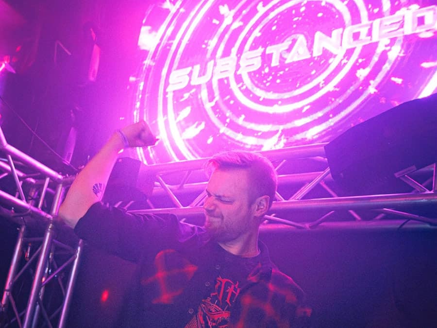 Substanced DJing in front of a glowing Substanced logo