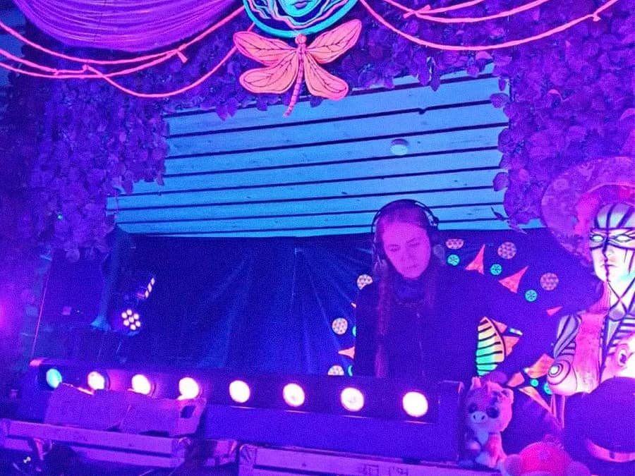DJ Ma’at playing in a UV-lit, decorated DJ booth