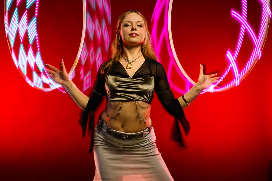 Annina Nova posing with glowing LED hoops against a red backdrop
