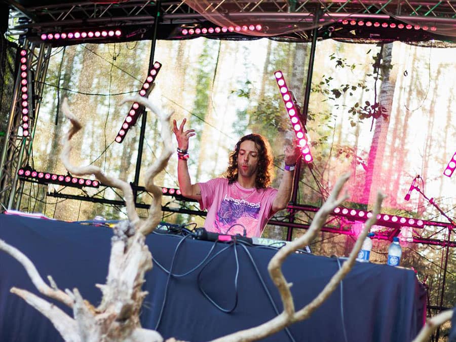 Räyhäviina raising a hand at the decks of a forest stage lit in pink