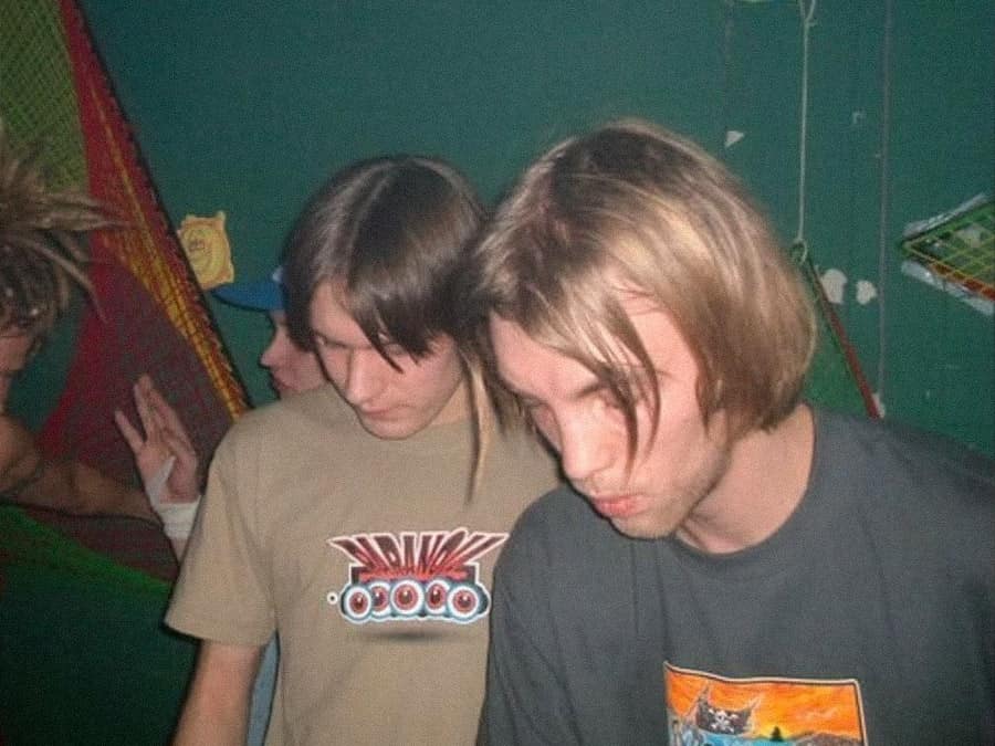 Two members of Tres Lost Amigos looking down at the decks in an old party photo