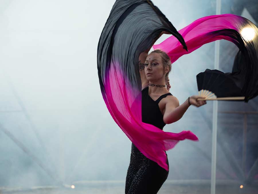 A dancer swirling pink and black silk fan veils