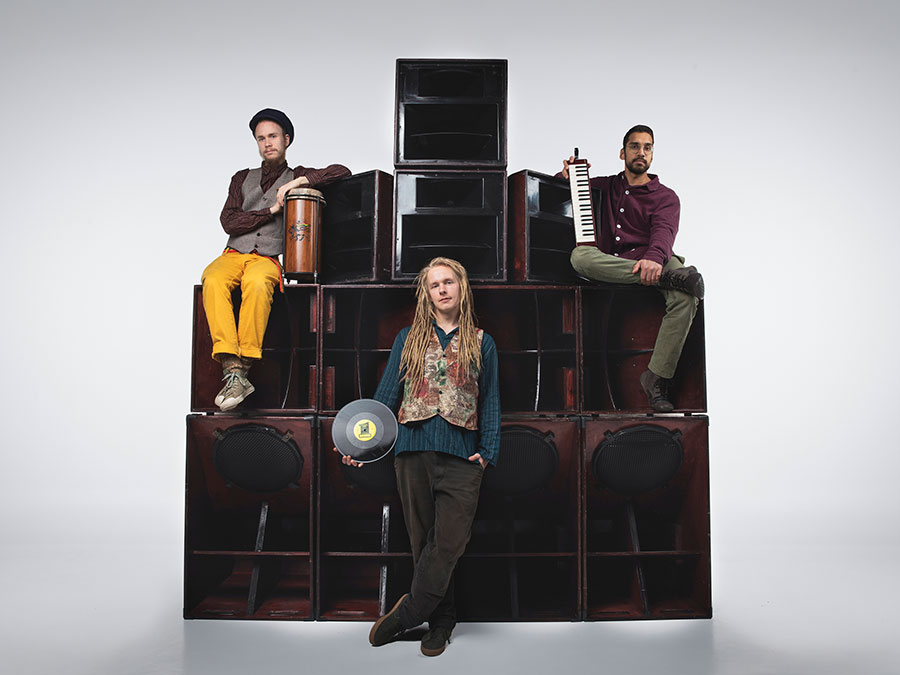 The three members of Salamar-Ites posing on a stack of sound system speakers