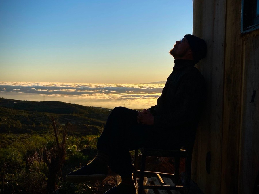 Sähköpaimen sitting in silhouette above a sunset landscape