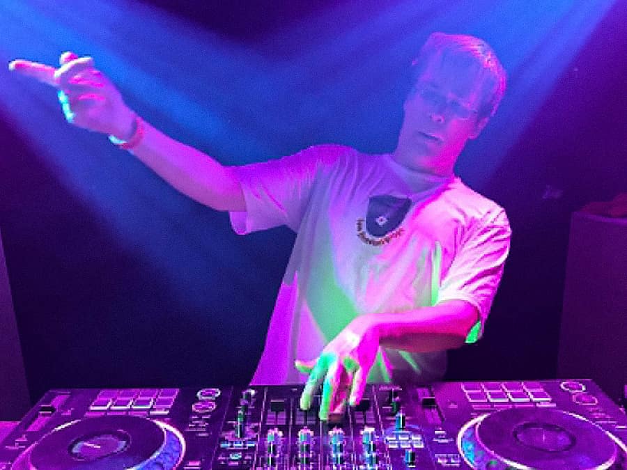 DJ Haemaerae pointing to the crowd from the decks under purple light