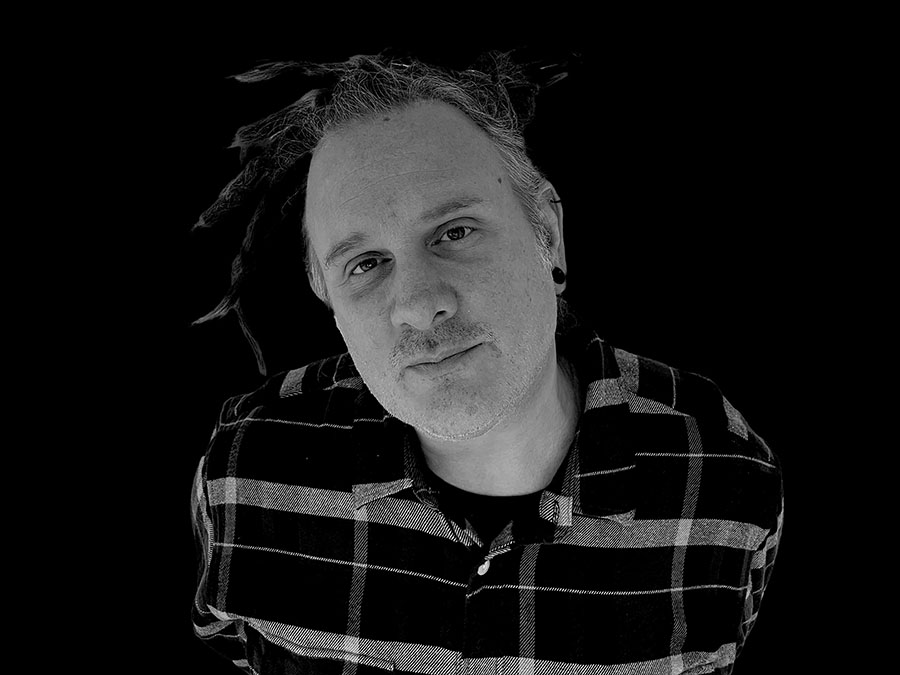 Black-and-white portrait of Eryk Orpheus in a checked shirt