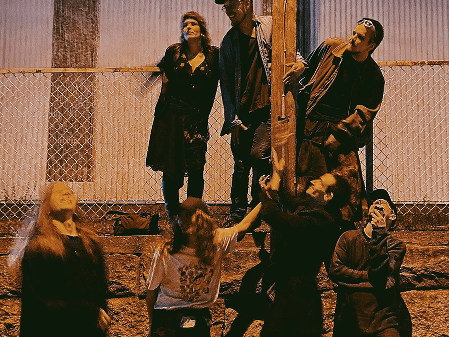 The double-diamond residents collective posing by a chain-link fence at dusk