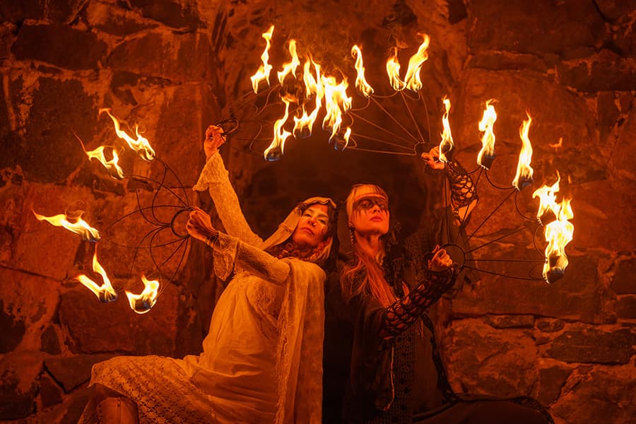 The two Fem Flamma performers with flaming fans in a stone archway