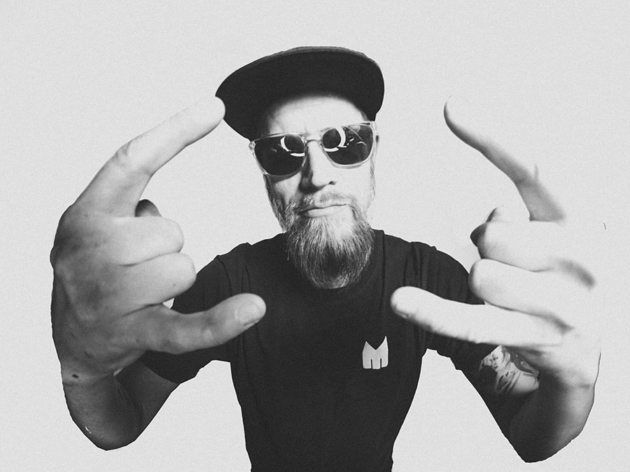Black-and-white photo of Pheat in a cap and round sunglasses gesturing with both hands