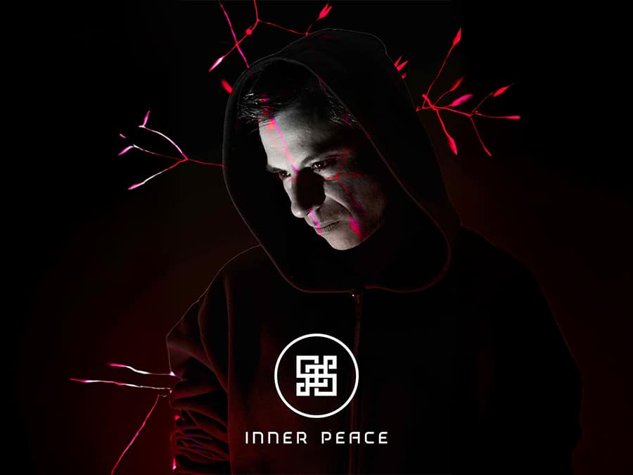 Hooded figure lit in red above the Inner Peace logo