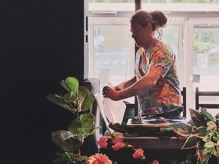 Kleptek at the turntables by a sunny window with plants and flowers