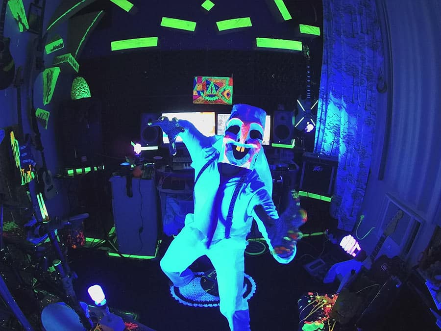 Hongos Longos performing in a mask and suit under UV light