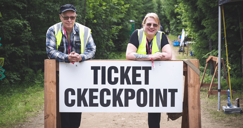 Two volunteers in high-visibility vests leaning on the ticket checkpoint sign. Photo: Alessandra Savarese