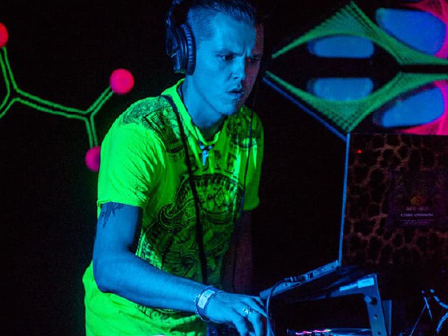 DJ Pandaala in a neon green shirt and headphones at the decks