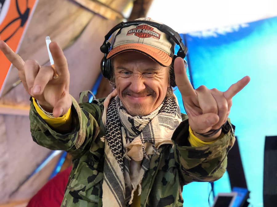 Sherebon in headphones and a cap, throwing the horns with both hands