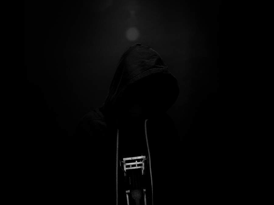 A hooded figure barely visible in darkness