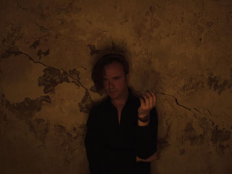Jori Hulkkonen standing against a cracked, dimly lit wall