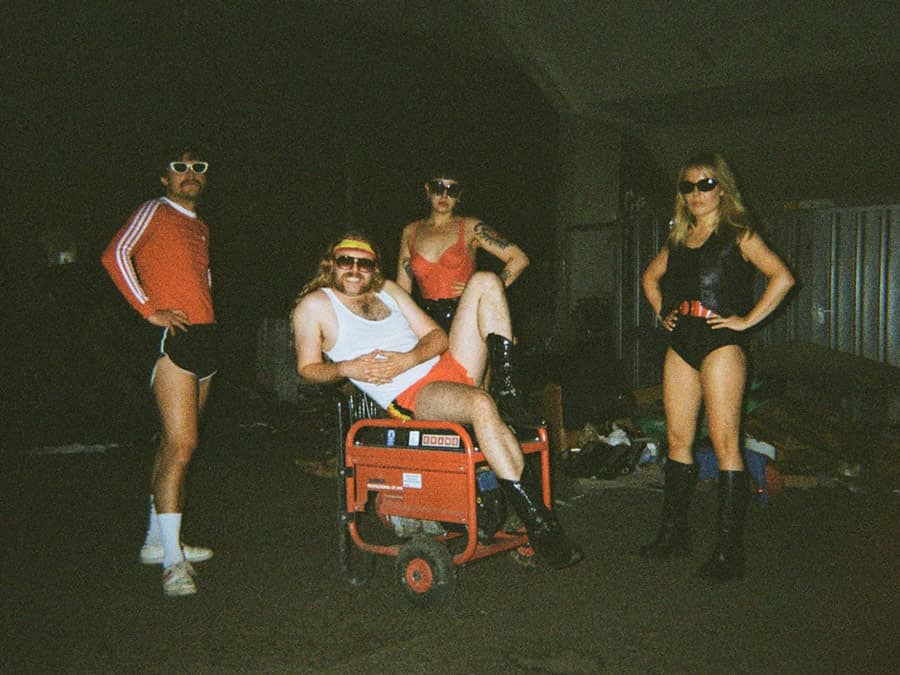 The four members of Satanen in retro sportswear, posing around a generator at night