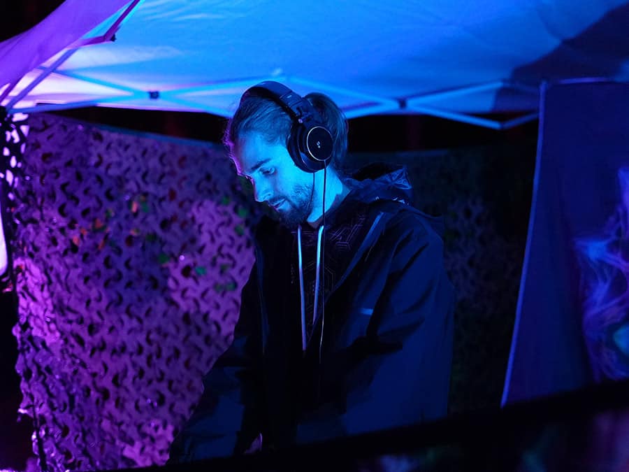 Lyserga in headphones at the decks under blue and purple lights