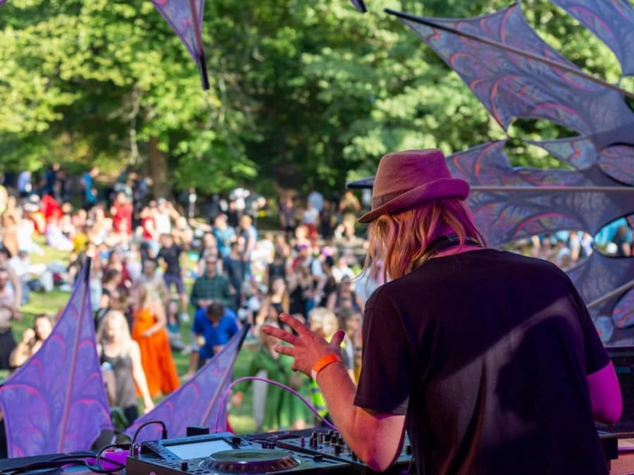 Oden, seen from behind, playing to a daytime crowd at a forest stage