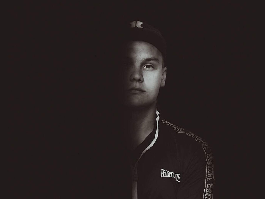 MWA in a cap, face half lit against a dark background