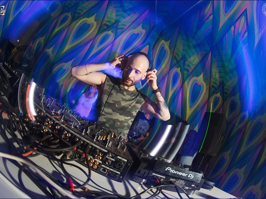 Tsubi holding his headphones at a mixer inside a psychedelic dome
