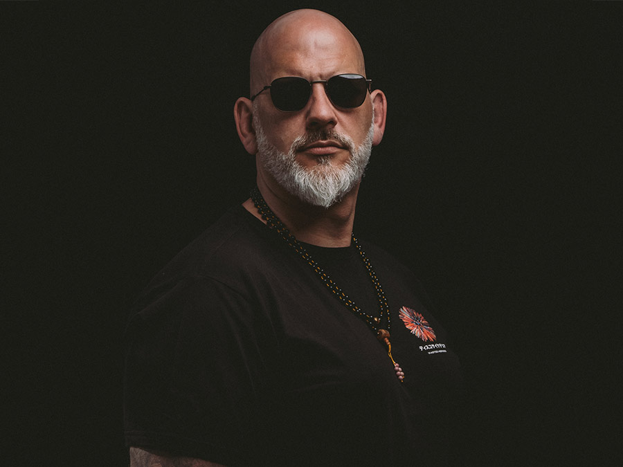 Rob Ótico in sunglasses with a grey beard, on a dark background