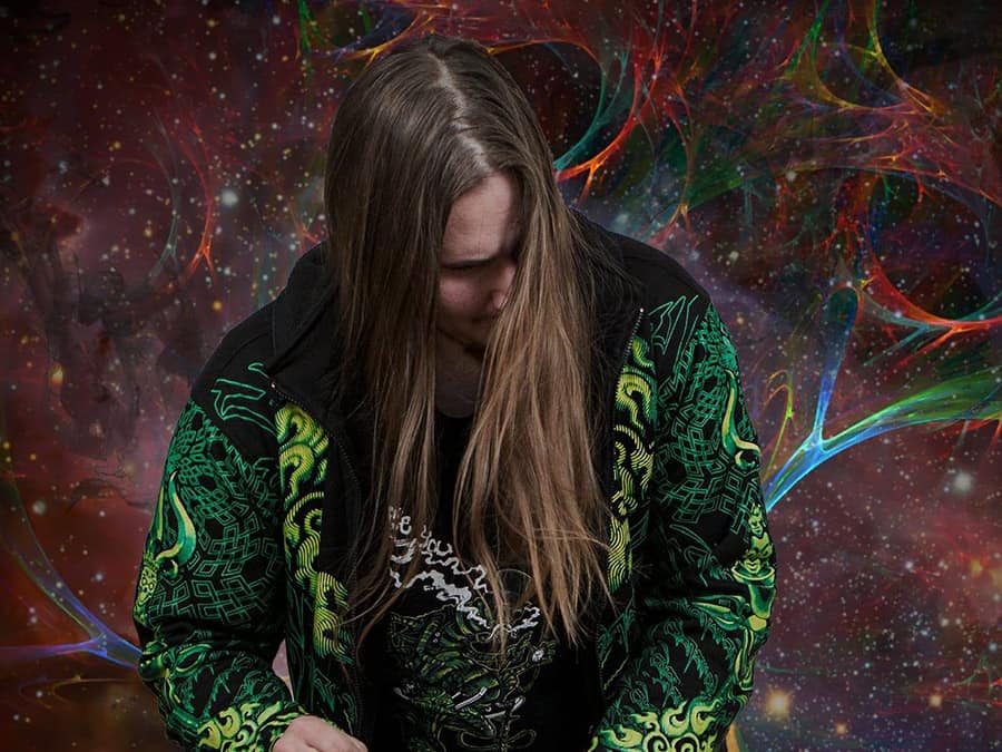 Acid Angel with long hair in a patterned hoodie against cosmic artwork