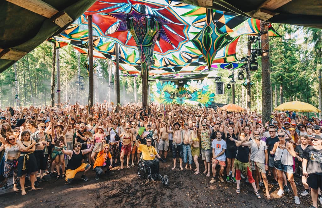 A cheering crowd under the colourful canopy of a forest stage at Kosmos Festival 2025. Photo: Gesina Sundström